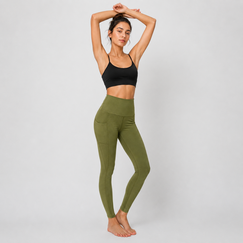 A woman modeling high-waisted olive green leggings and a black sports bra against a light gray studio background.