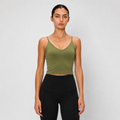A woman modeling a fitted olive green spaghetti-strap crop top with black high-waisted leggings, standing against a light gray studio background.